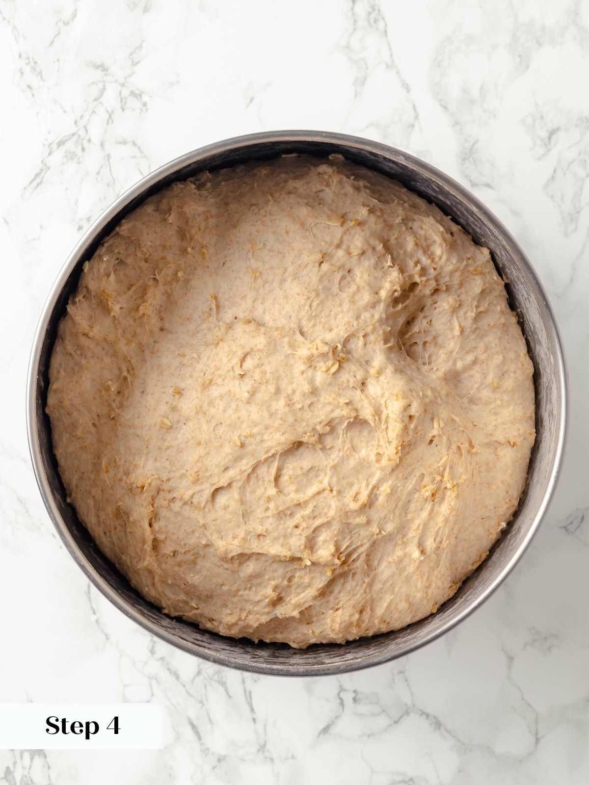 Proofed oatmeal bread dough in a bowl, ready to shape.