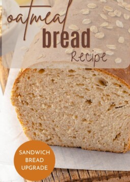 Loaf of honey oatmeal bread on wooden cutting board.