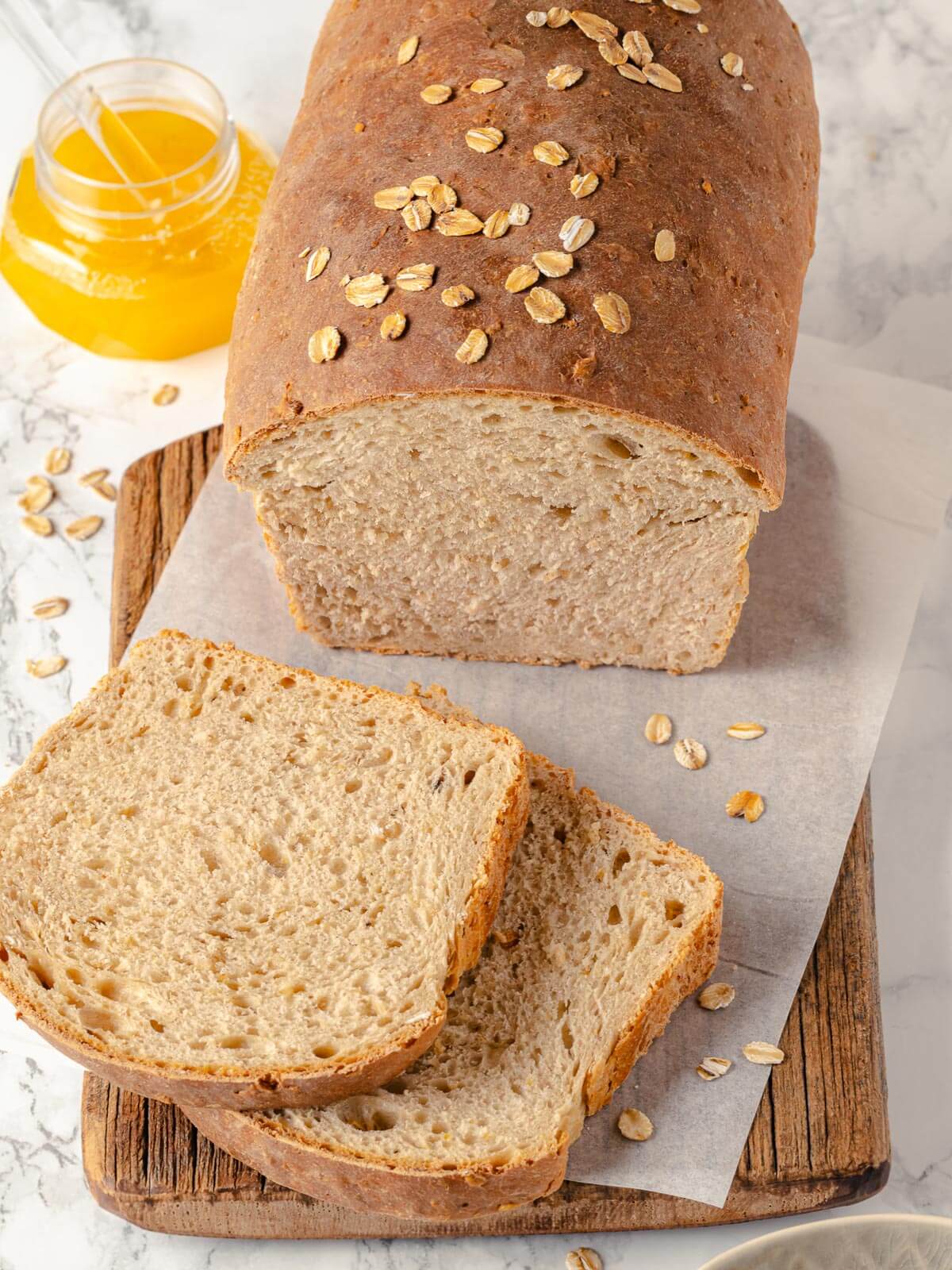 Two slices of oatmeal bread stacked on a wooden board.