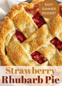 A whole strawberry rhubarb pie with golden crust on a table.