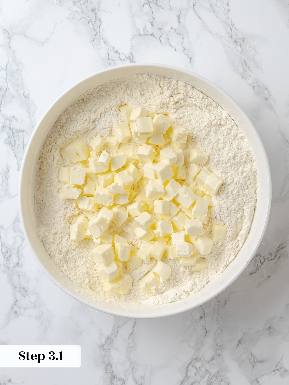 Chunks of butter added to flour mixture in a bowl.