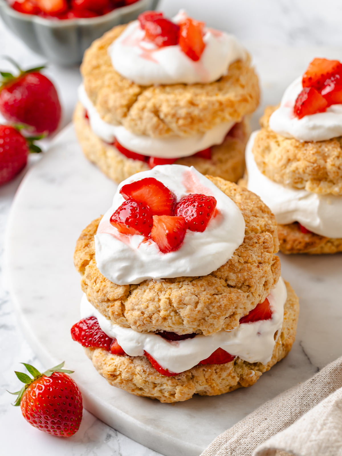 Three complete strawberry shortcakes arranged side by side.
