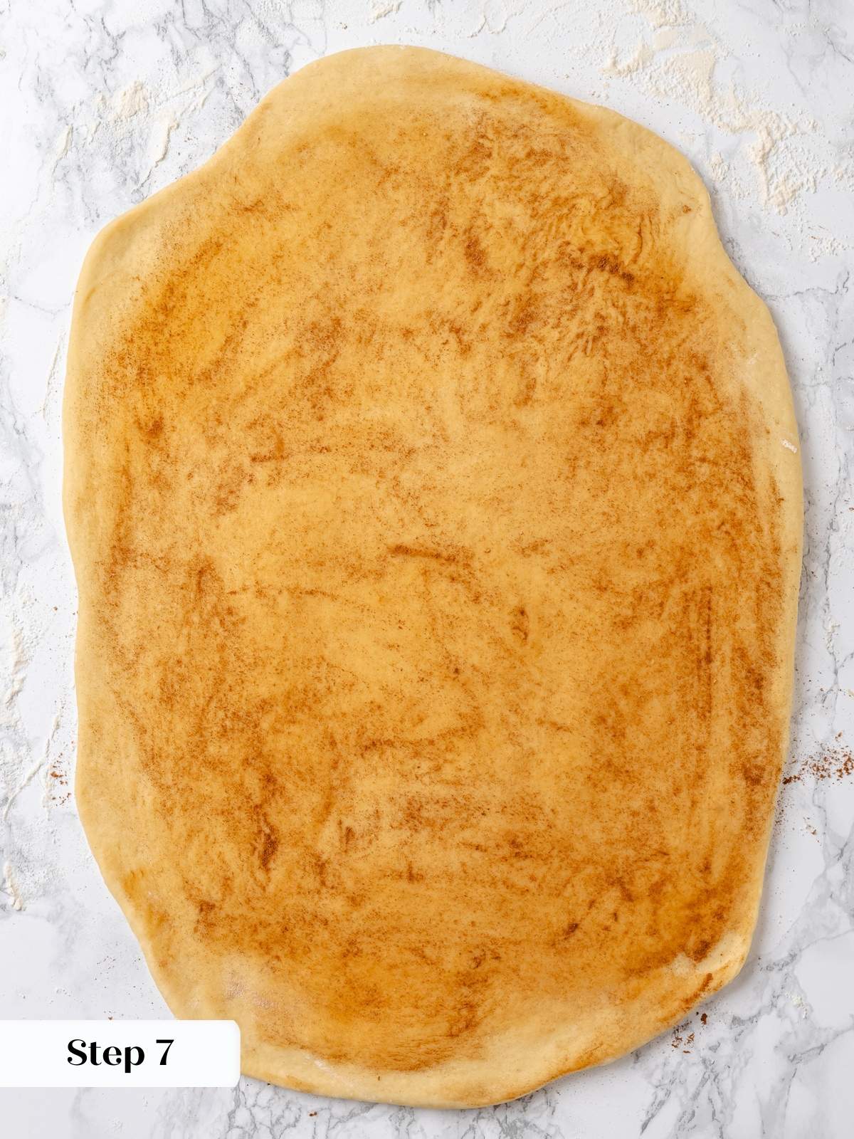 Ground cinnamon sprinkled over flattened dough.