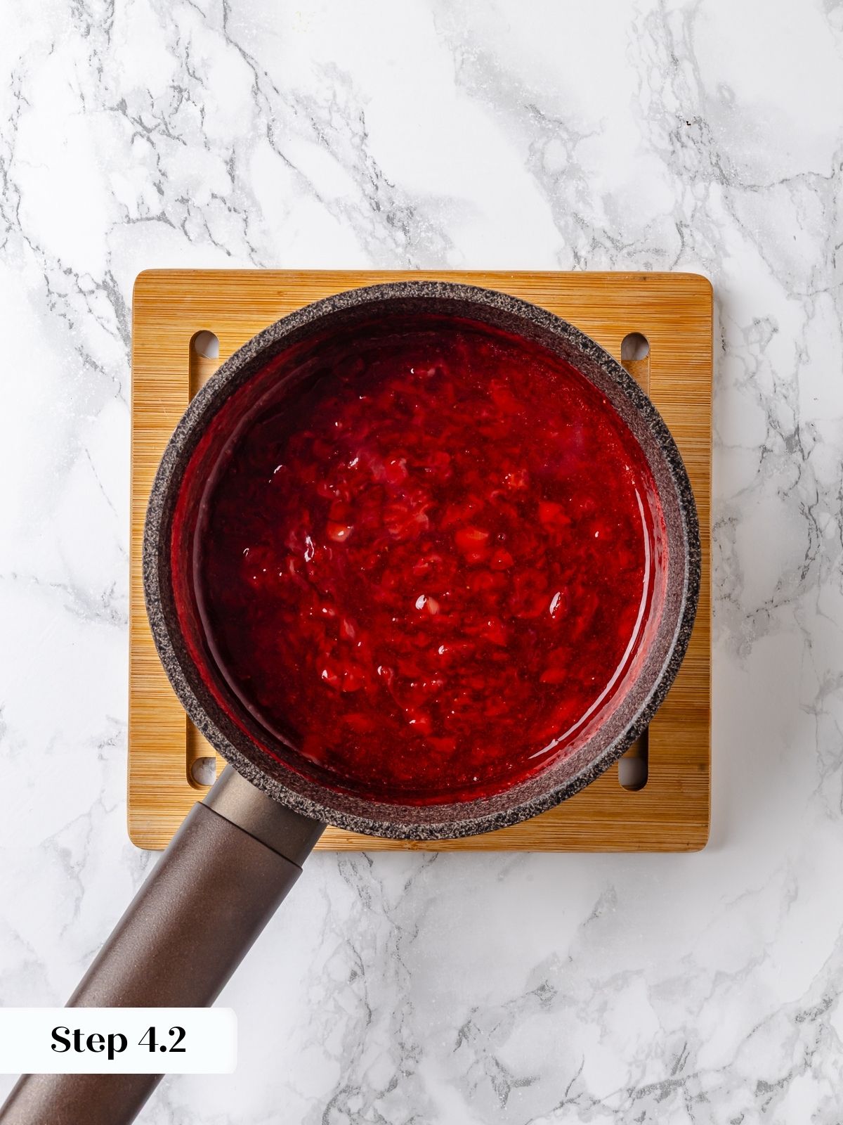 Strawberry jam simmered in a metal pot.