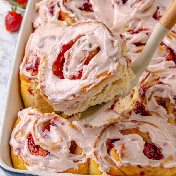 Spoon lifting a gooey strawberry cinnamon roll.