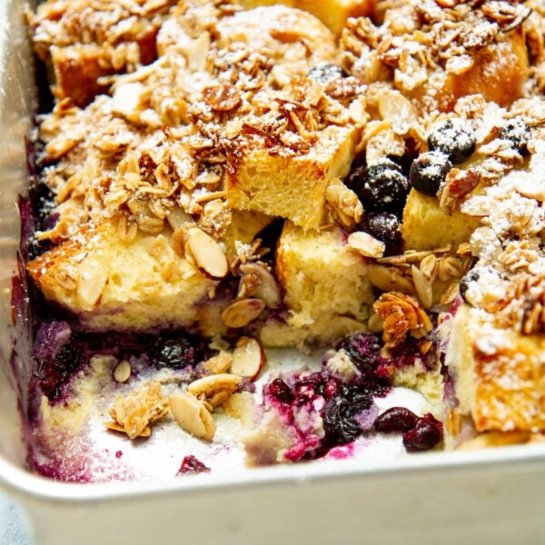 Baked French toast casserole with golden streusel topping and blueberries visible on the surface.