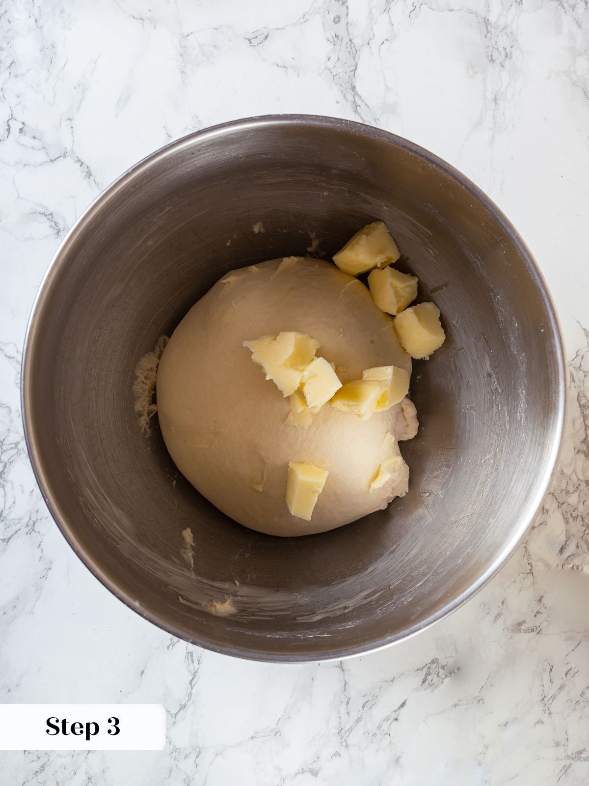 Adding small butter pieces into mixing dough during sourdough sandwich bread recipe preparation.