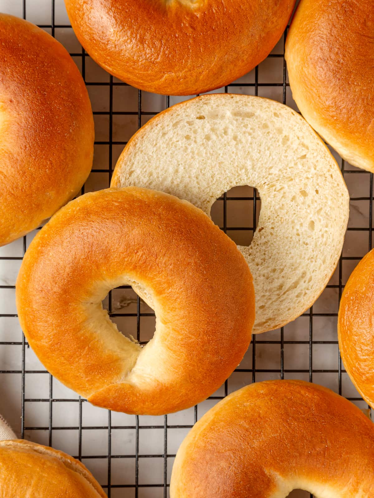 Several bagels gathered on a cooling rack highlighting their soft centers and golden shells.