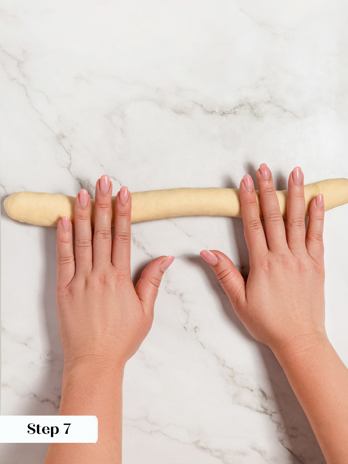 Dough being rolled into a long log shape preparing it to become a bagel rope.