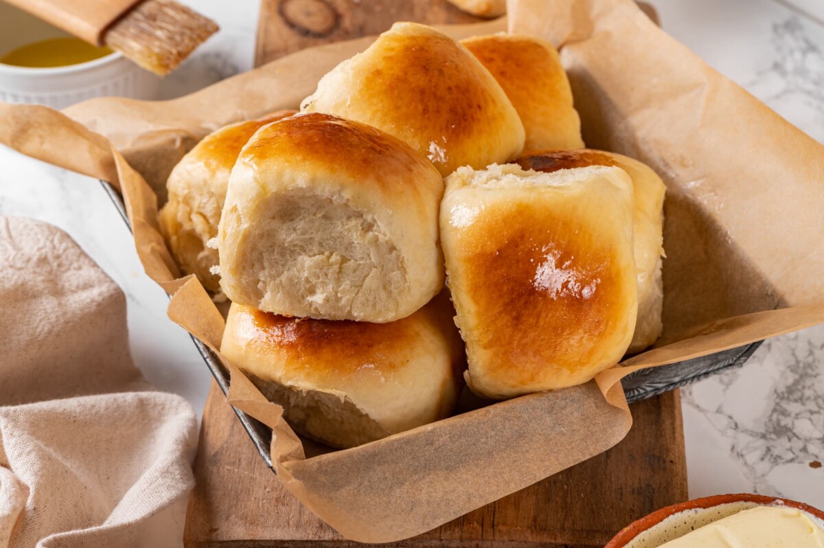 Multiple sourdough dinner rolls gathered in a tall pile highlighting their tender baked texture.