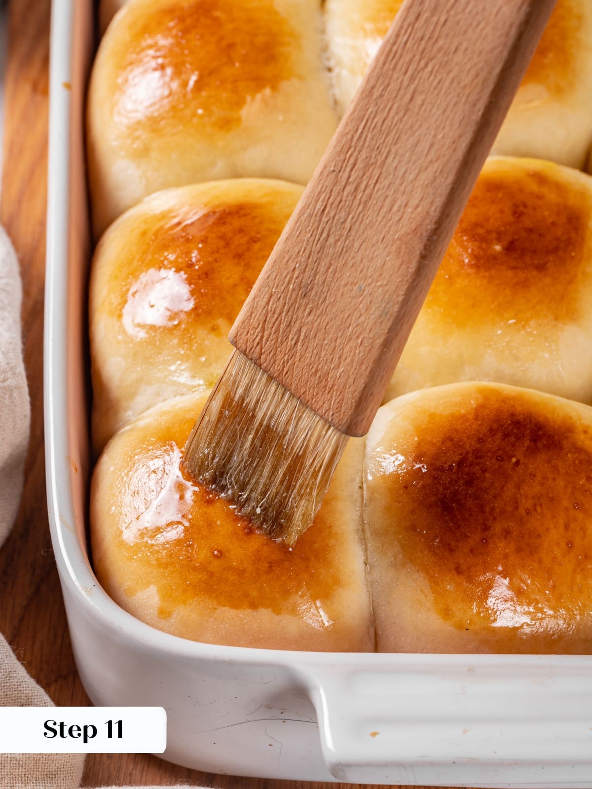 Fresh rolls receiving a melted butter brushing to enhance softness and warm flavor.