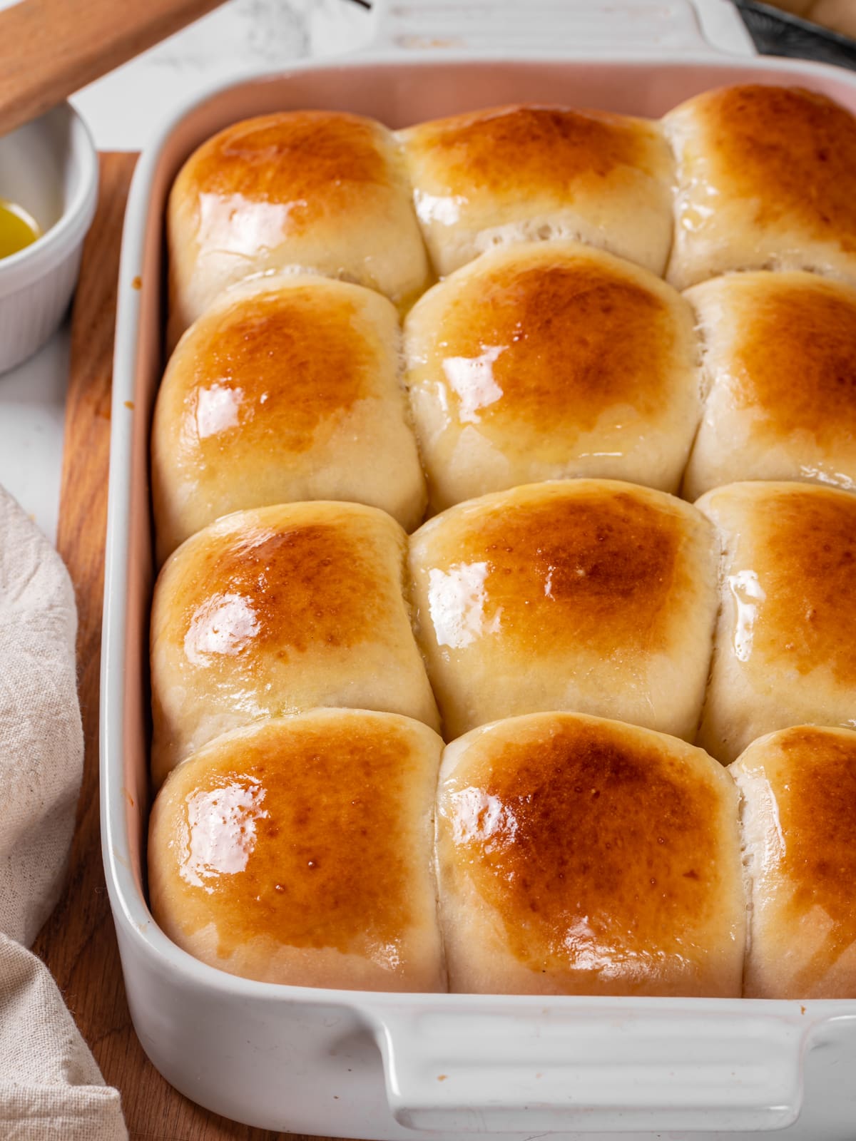 Soft rolls showing a gentle shine on top arranged closely in their baking dish.