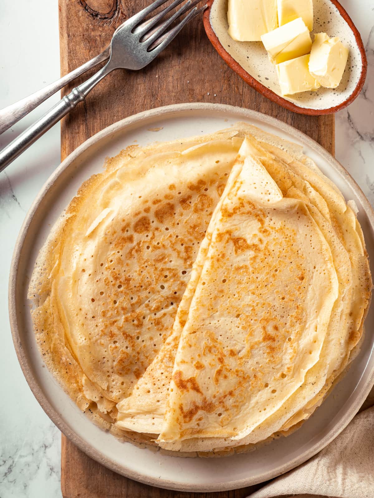 Folded sourdough crêpes arranged neatly on a plate ready for sweet or savory fillings.