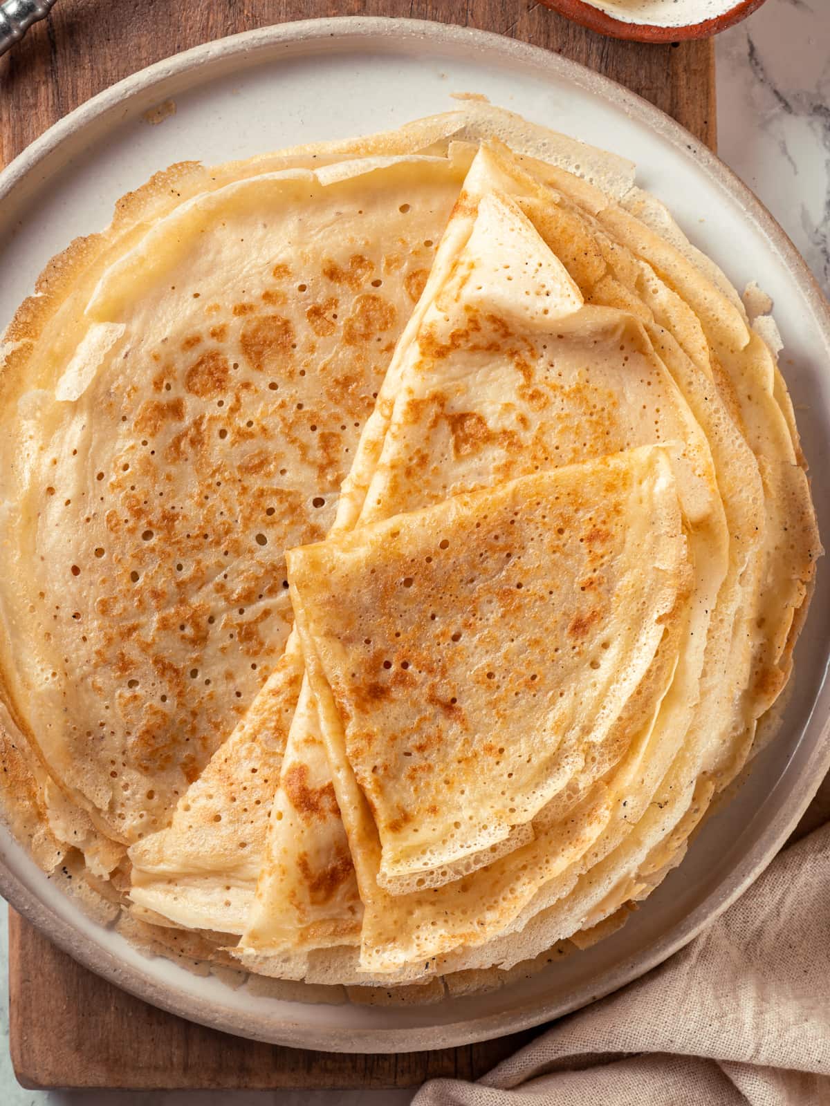 Golden sourdough crêpes stacked neatly on a plate ready to serve.
