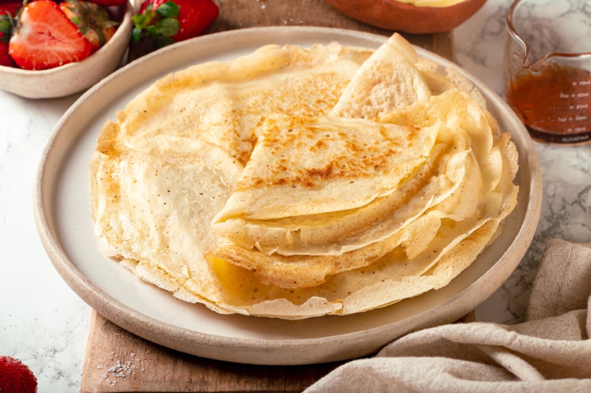 Folded sourdough crêpes layered into a neat stack on a plate.