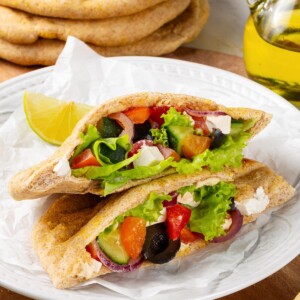 Stuffed whole wheat pita holding vegetables and greens for lunch.