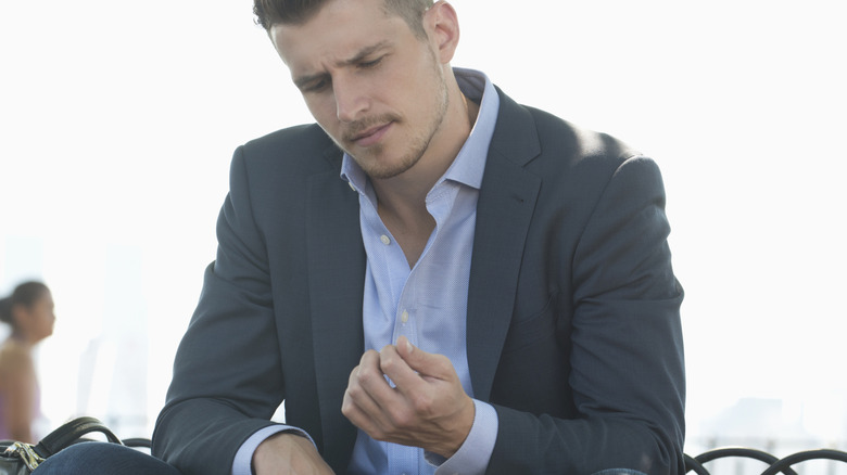 confused man in suit looking at his nails