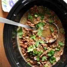 Crock pot with frijoles borrachos and cilantro.