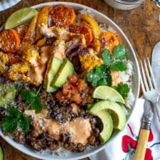 A healthy vegetarian burrito bowl next to a jar of Cotija cheese