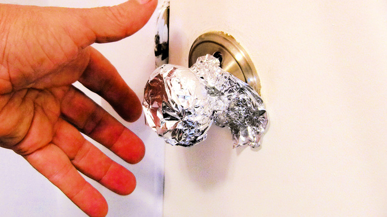 doorknob with aluminum foil and a man's hand