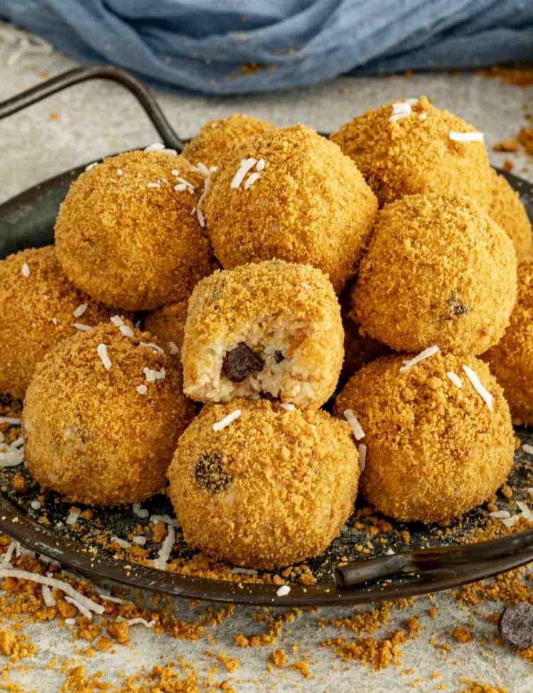 Moose Farts arranged on a dark tray, one with a bite revealing the chocolate chip center and soft coconut filling.