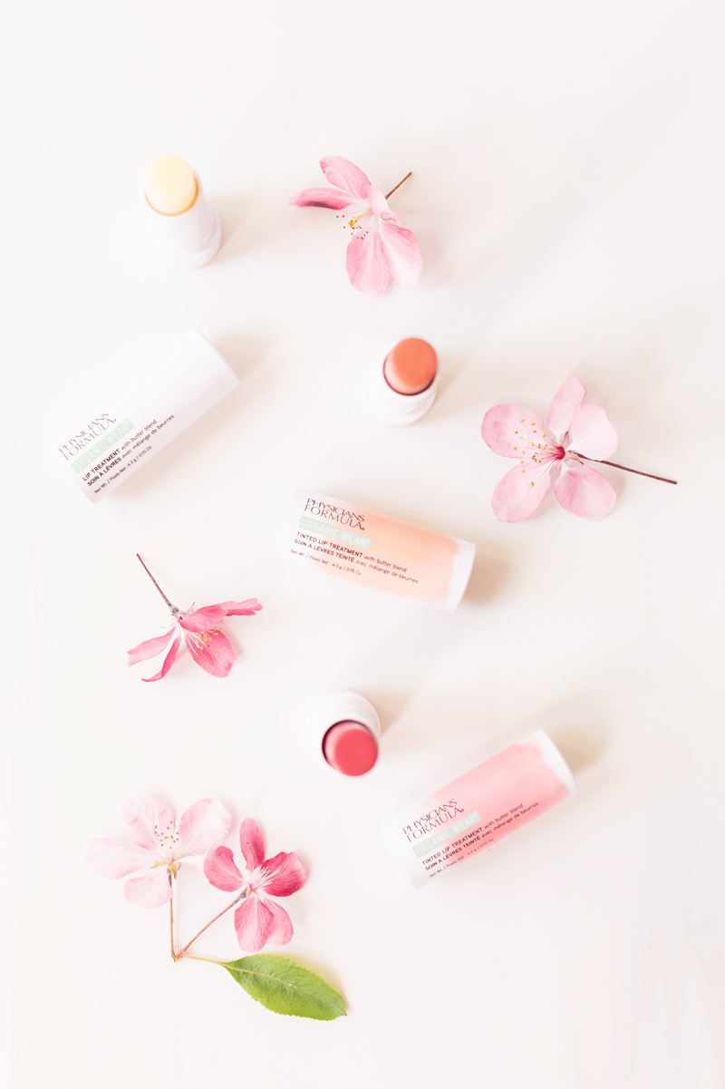 My Top 5 Physicians Formula Products | JustineCelinaβs most worn Physicians Formula Products | JustineCelinaβs favourite lipsticks | Beauty Bloggerβs Favourite Physicians Formula Products | Physicians Formula Organic Tinted Lip Treatment in Tickled Pink, Tawny Nude and Clear Photos Review Swatches | Best Cruelty Free Drugstore Lip Balms 2020 | Physicians Formula Organic Wear Tinted Lip Treatment on a white background with cherry blossoms | Calgary Beauty Blogger // JustineCelina.com