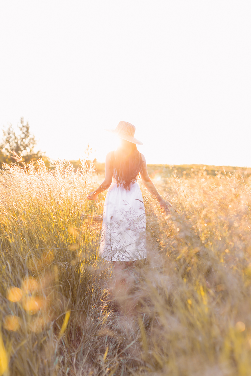 Summer 2020 Lookbook | Boho Summer 2020 Outfit Ideas | Summer Capsule Wardrobe | Summer Quarantine Outfits | Classic Summer Outfit Ideas | The Best Linen Dresses 2020 | The Best Little White Dresses 2020 | Classic Linen Sundress | Summer Outfit Ideas | Classic Affordable Summer Style | Summer 2020 Trends | Brunette woman wearing H&Mβs Linen-Blend Dress in White with a Straw Hat in a Picking Wheat holding a Wicker Basket at Golden Hour | Calgary Alberta Fashion Blogger // JustineCelina.com