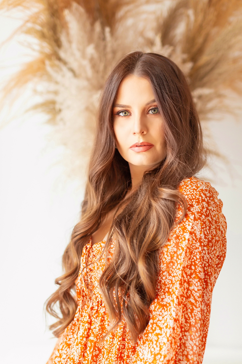 My Top 5 Pumpkin Spice Lipsticks | JustineCelinaβs most worn Physicians Formula Products | Beauty Bloggerβs Favourite Physicians Formula Products | Physicians Formula Organic Wear Tinted Lip Treatment in Gingersnap Photos Review Swatches | The Best Drugstore Fall Lipsticks | The Best Pumpkin Spice Lipsticks for Fall | Fall Lipstick Trends | Brunette woman wearing an orange floral dress and fall nude lipstick with pampas grass in the background | Calgary Beauty Blogger // JustineCelina.com