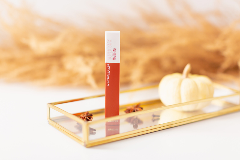 My Top 5 Pumpkin Spice Lipsticks | JustineCelinaβs favourite fall lipsticks | The Best Pumpkin Spice Lipsticks for Fall | Fall 2020 Lipstick Trends | Maybelline Super Stay Matte Ink in Globetrotter Photos, Review, Swatches and Dupes | Light / Medium Skintone | The Best Drugstore Fall Lipsticks | The Best Pumpkin Spice Lipsticks for Fall | Lipstick on a Mirrored Tray with spices, a white mini pumpkin and pampas grass in the background | Calgary Beauty Blogger // JustineCelina.com