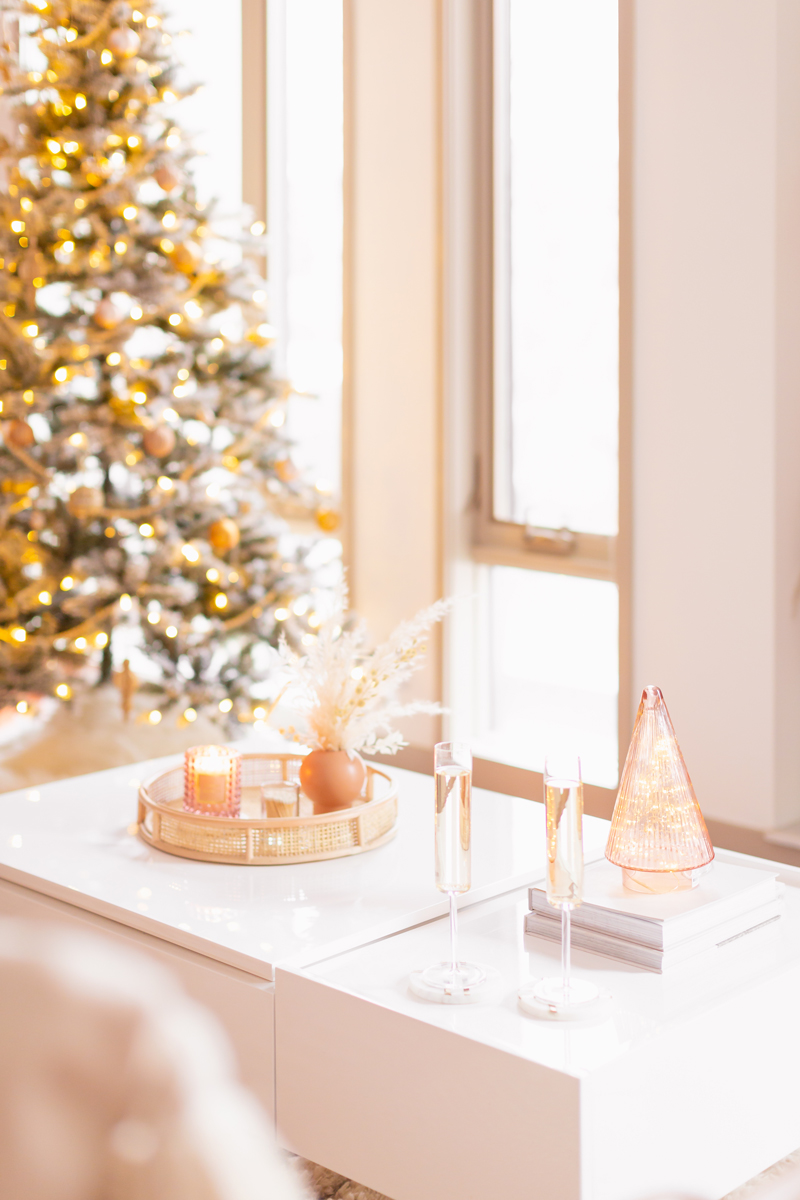 Mid Century Meets Boho Holiday Decor | Bright and airy Mid Century Modern Living Room with a Flocked Christmas Tree and Champagne Glasses on a White Coffee Table | Boho Christmas Decorating Ideas for Apartments | Flocked Christmas Tree with Wood Garland, Metallic and Wood Ornaments | Bohemian Holiday Home Tour 2020 | Boho Chic Christmas Decor | Glam neutral holiday decor | Pampas Grass Holiday Arrangement | Boho Christmas Tree | Crate & Barrel Edge Champagne Glasses // JustineCelina.com