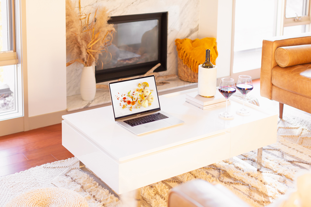 DIGITAL BLOOMS NOVEMBER 2021 | 11 Free Downloadable Floral Tech Backgrounds for Fall | A cozy bohemian Living Room with a marble fireplace and white coffee table with a MacBook Pro featuring JustineCelinaβs November Digital Blooms floral and pumpkin tech wallpaper and two glass of red wine | Female Entrepreneur Digital Wallpapers | The Best of Justine Celinaβs Fall Digital Blooms | Fall Flower Desktop Wallpaper | Calgary Creative Lifestyle Blogger // JustineCelina.com