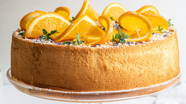 Whole chiffon cake on cake stand, garnished with fresh orange slices
