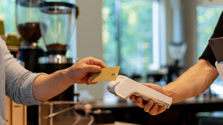 Barista holding a terminal POS as a cafe customer tips