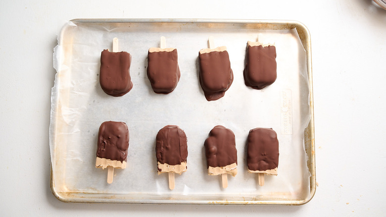 frozen chocolate covered popsicles on a sheet tray