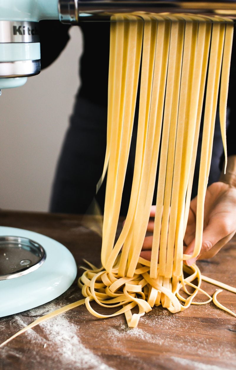 Fresh homemade fettuccine pasta coming through the Kitchen Aid stand mixer pasta attachment.