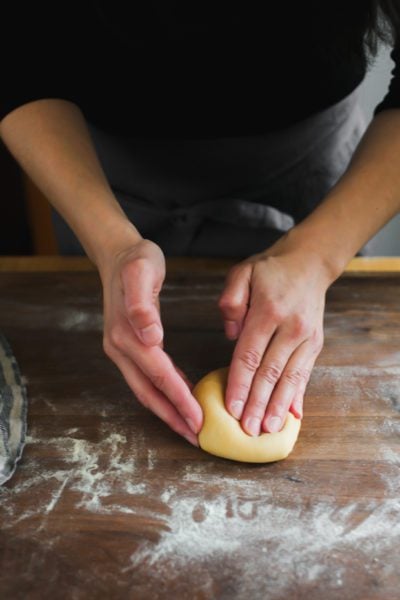 Flattened pasta dough into an oval shaped disc.