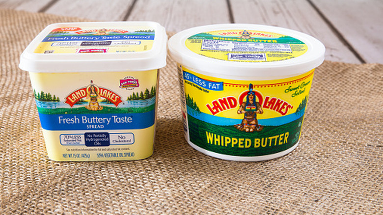 A tub of Land O'Lakes butter spread and a tub of Land O'Lakes whipped butter on an outdoor table