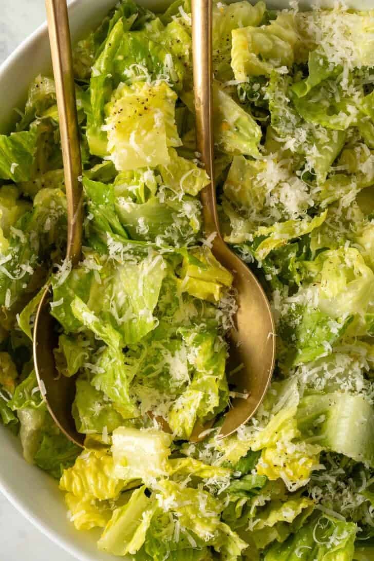 Lemon Parmesan Lettuce Salad Lemon Parmesan Lettuce Salad in a white bowl with golden salad servers.